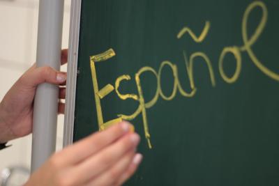 teacher writing "Espanol" on green chalkboard
