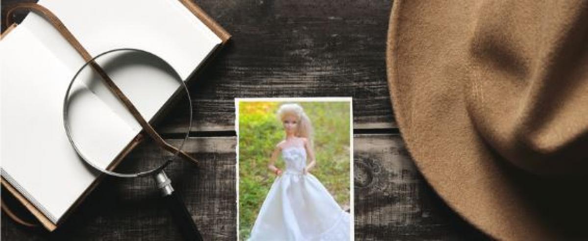 detective hat with notebook and magnifying glass and photo of Barbie doll in wedding dress